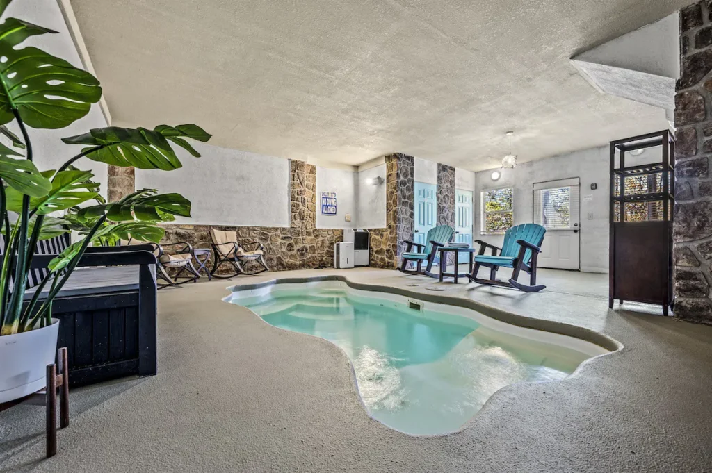 Indoor pool with stone walls, rocking chairs, and plants